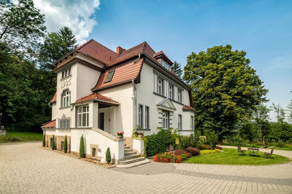 une maison blanche avec un toit rouge dans l'établissement Villa Adam, à Pieszyce
