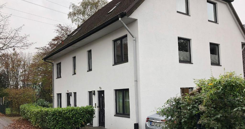 a white house with a car parked in front of it at Hansa Apartments Hamburg in Hamburg