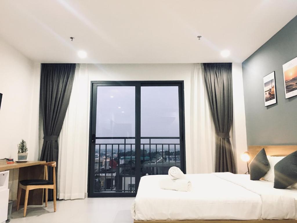 a bedroom with a bed and a large window at The Green House - Serviced Apartment in Thu Dau Mot