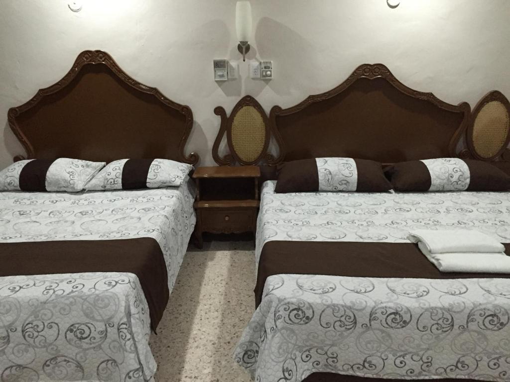 two beds in a hotel room with two bedsitures at Hostal Kin-Beh in Valladolid
