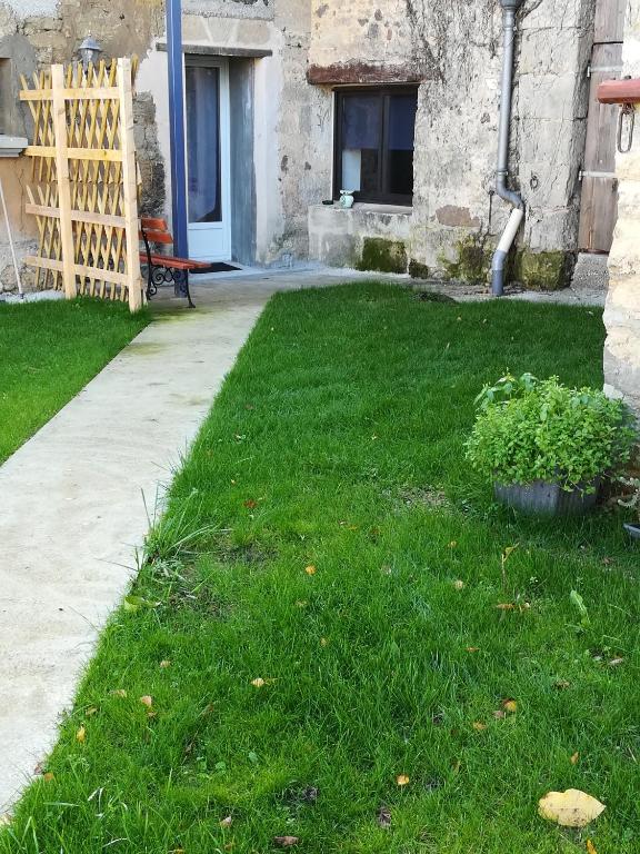 une cour avec de l'herbe verte et un banc devant un bâtiment dans l'établissement La Grange du Layon, à Saint-Georges-sur-Layon