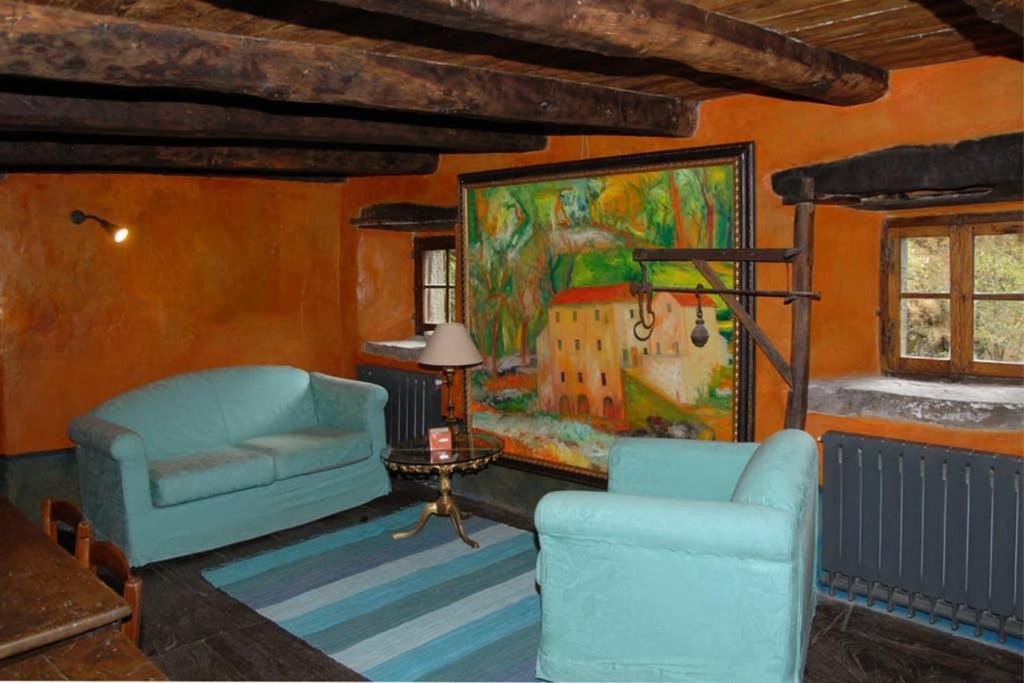Mulino Francesco Saverio في Pieve Fosciana: غرفة معيشة مع كرسيين و لوحة على الحائط