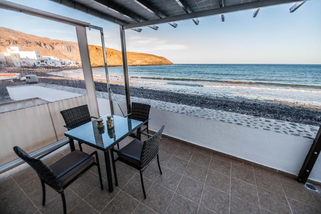 Tito´s Beach House في Pozo Negro: طاولة وكراسي على شرفة مطلة على الشاطئ