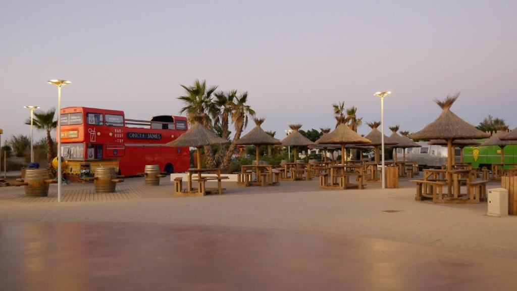 un bus rouge à deux étages garé dans un parking dans l'établissement Mobil home au castellas marseillan, à Sète
