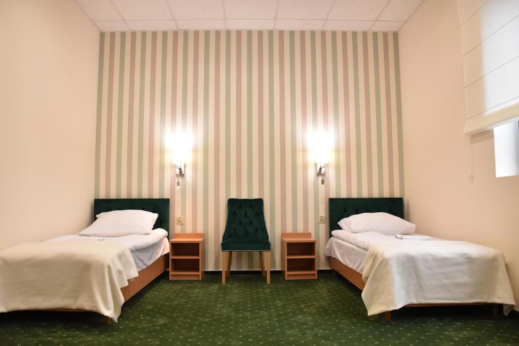 a hotel room with two beds and two chairs at Pokoje Gościnne DACPOL in Piaseczno