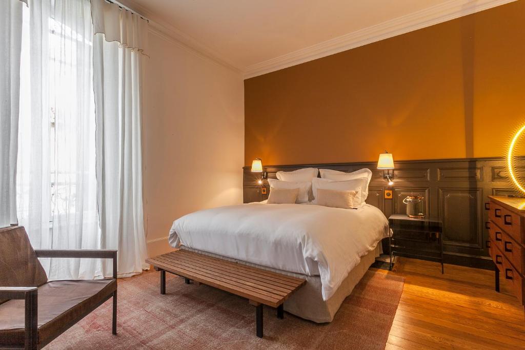 a bedroom with a large white bed and a chair at Maison TANDEM in Cluny