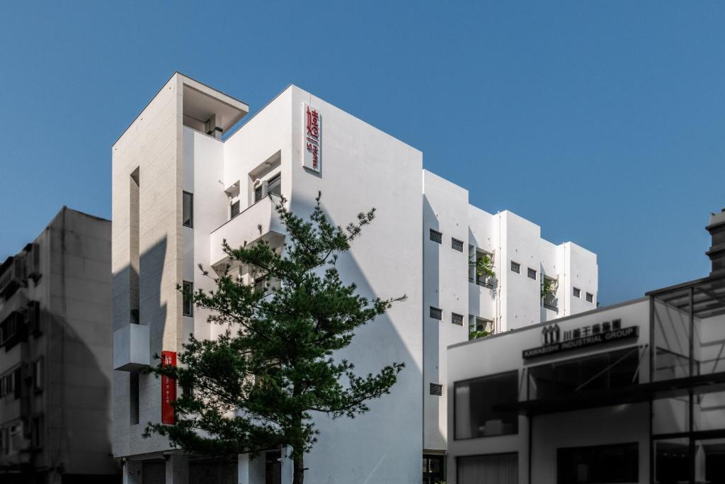 un edificio bianco con un albero di fronte di SI Hotel a Taichung