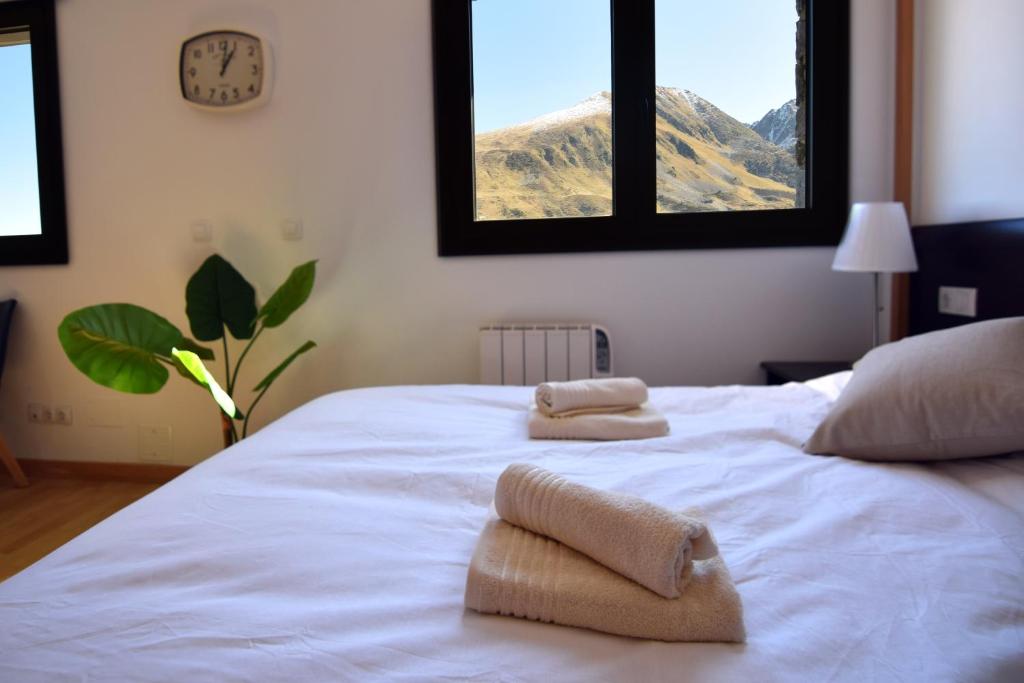una camera da letto con un letto bianco e asciugamani di Lux Aigle "Acceso directo a pistas" a Pas de la Casa