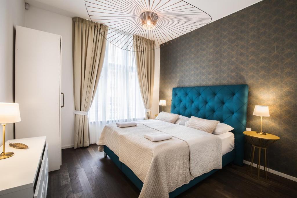 a bedroom with a blue bed and a window at Modern Designed Oldtown Square Apartment in Prague