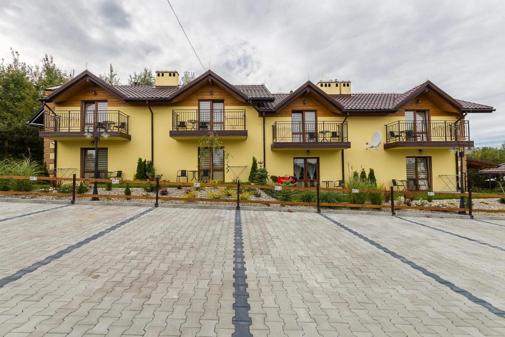 a yellow house with a brick driveway in front of it at Ośrodek Wypoczynkowy Cypel in Polańczyk