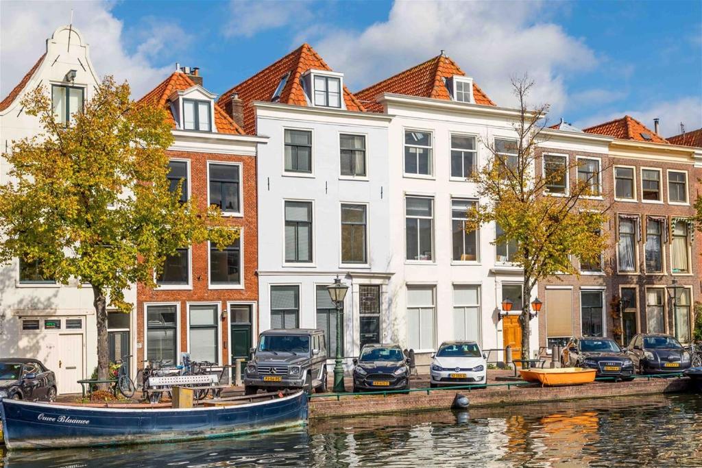 um grupo de edifícios junto a um rio com um barco em B&B Hart van Leiden em Leiden