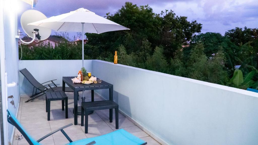 a table and chairs on a balcony with an umbrella at joli appartement avec vue au Moule in Le Moule