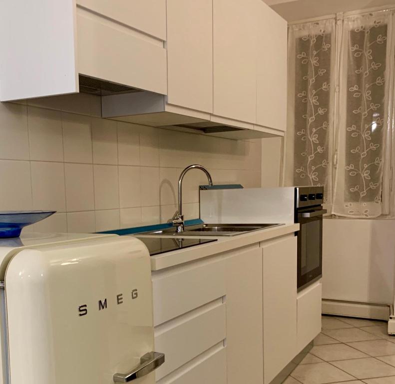 uma cozinha branca com um lavatório e um frigorífico em [Storico] Ombelico di Parma em Parma
