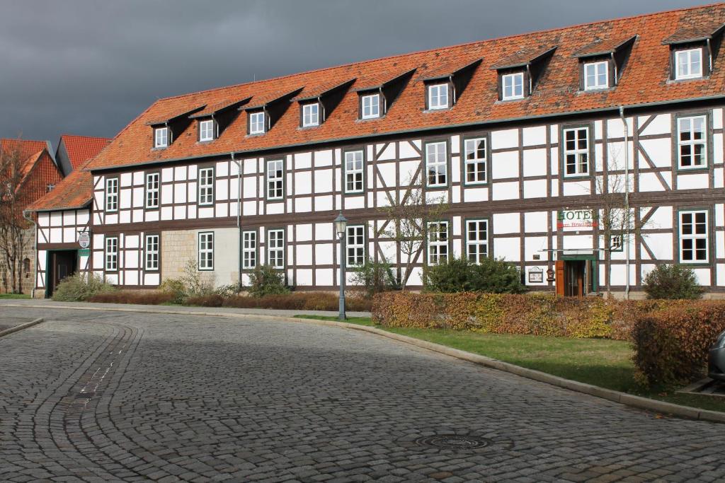 un grand bâtiment blanc avec un toit rouge dans une rue dans l'établissement Hotel zum Brauhaus, à Quedlinbourg