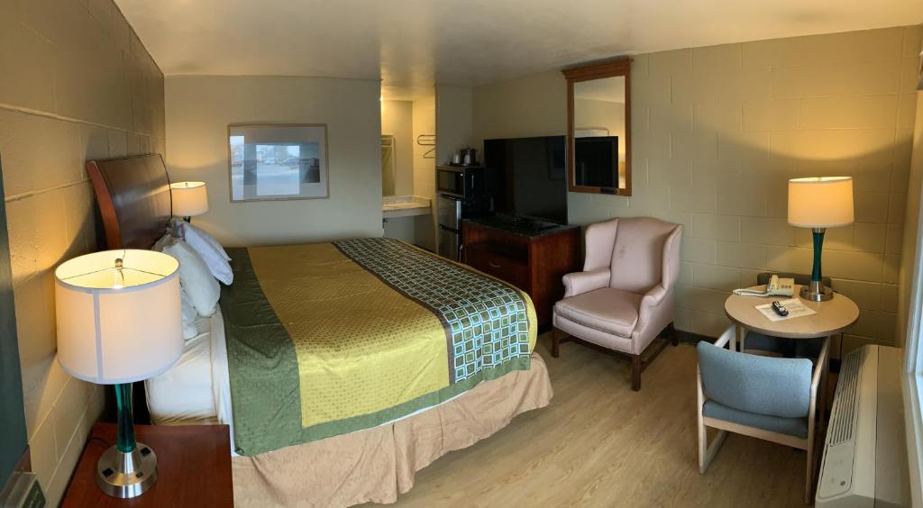 a hotel room with a bed and a chair at Super 7 Inn in Wright City