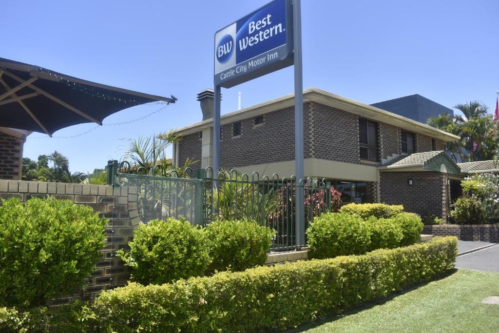 a sign in front of a house with bushes at Best Western Cattle City Motor Inn in Rockhampton