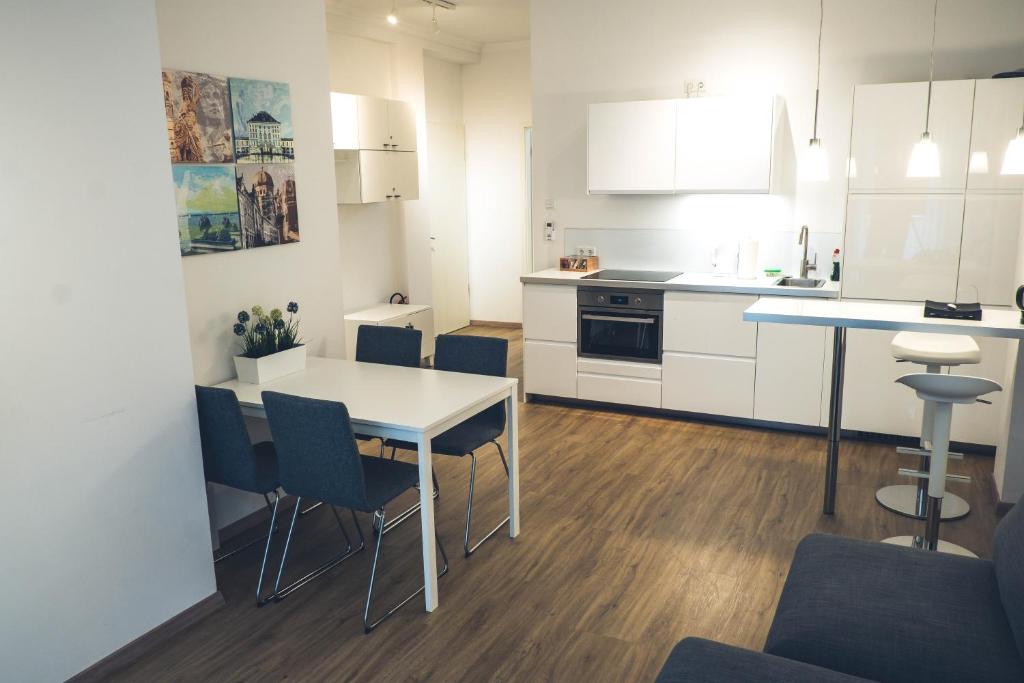 a kitchen with white cabinets and a table and chairs at Stylisch eingerichtete Wohnung mitten in München! in Munich