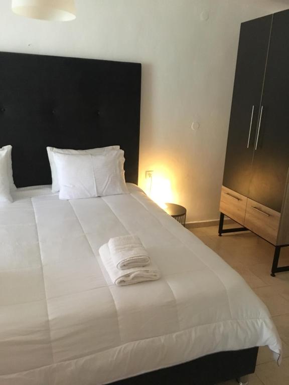 a bedroom with a white bed with a black headboard at Camping Stolos in Limín Litochórou