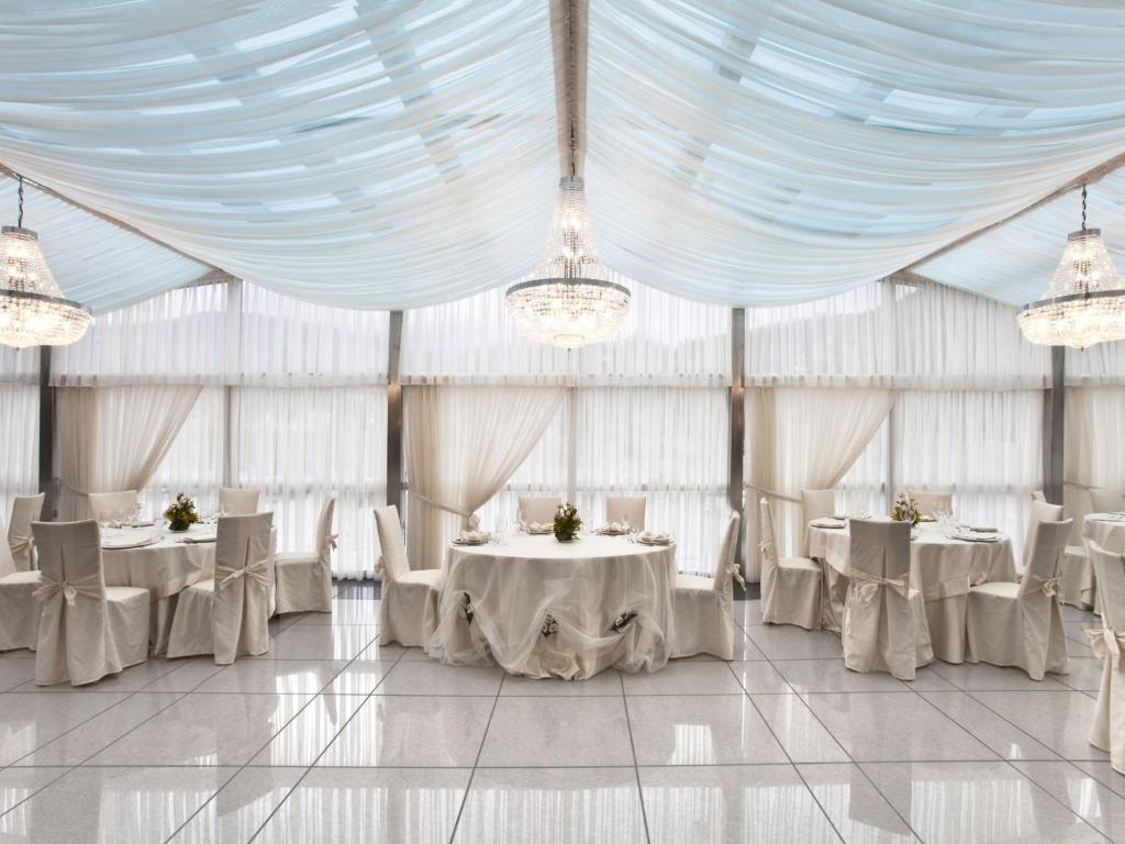 een tent met witte tafels en stoelen en kroonluchters bij Hotel Dei Principati in Baronissi
