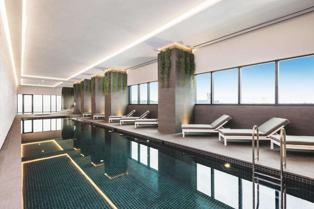 a swimming pool with chairs and tables in a building at Sky One Apartments by CLLIX in Box Hill