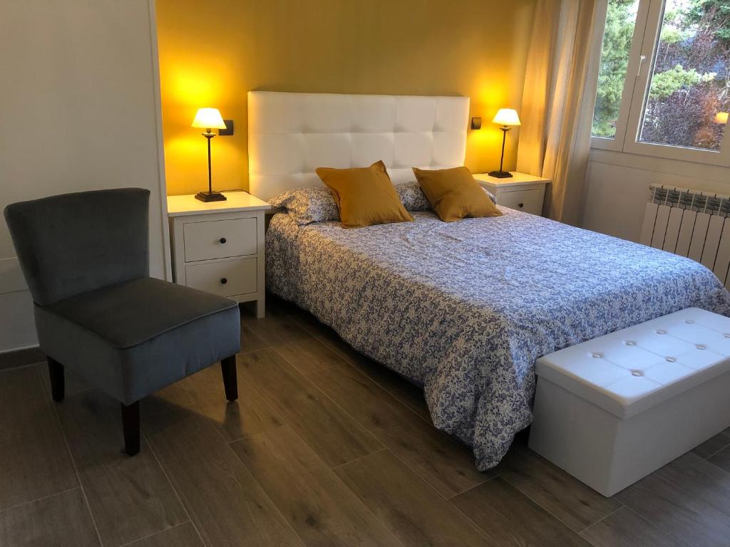 a bedroom with a bed and a chair and two lamps at CASA VILLACERRADA in Navacerrada