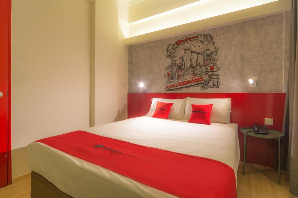 a bedroom with a red and white bed with red pillows at RedDoorz at Geylang in Singapore