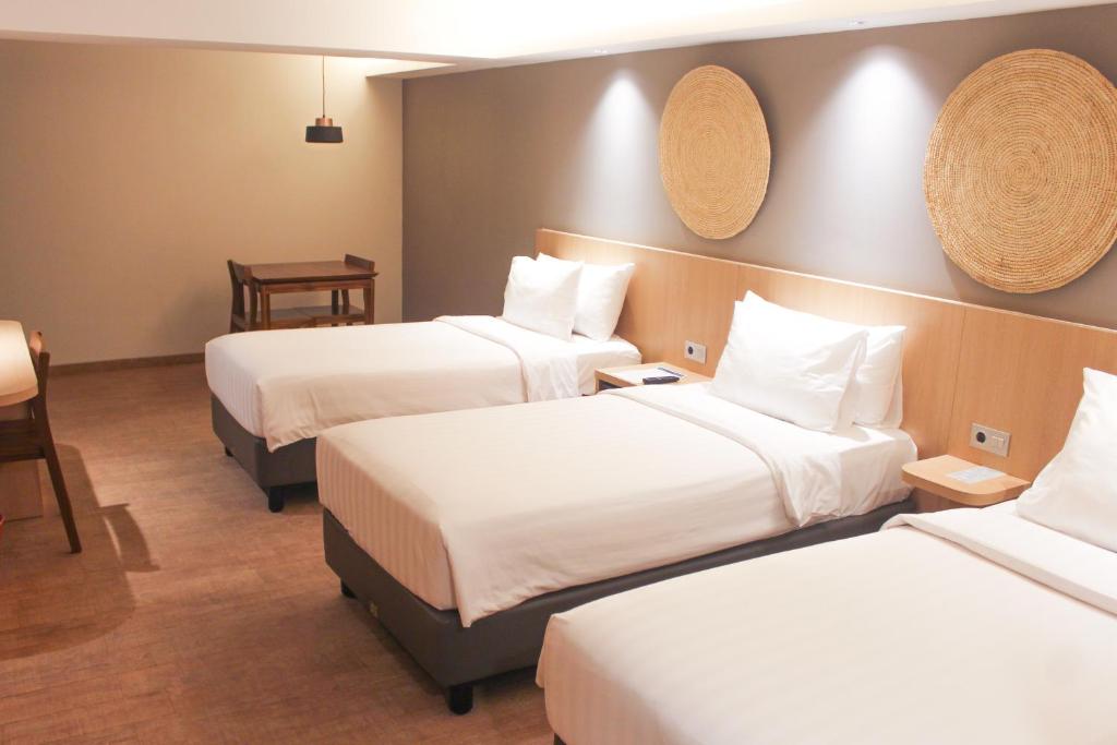 a hotel room with two beds and a table at Aveta Hotel Malioboro in Yogyakarta