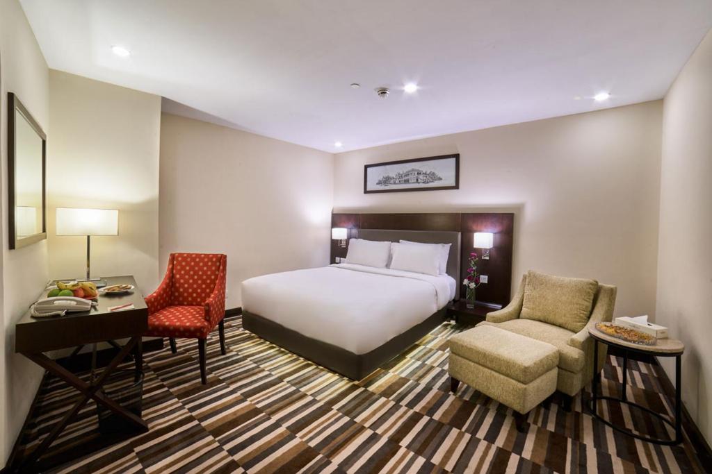 a hotel room with a bed and a desk and chairs at Avari Xpress Gulberg in Lahore