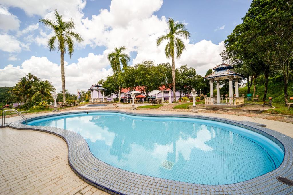 a swimming pool with a gazebo and palm trees at Hotel O Kulim Inn in Kulim