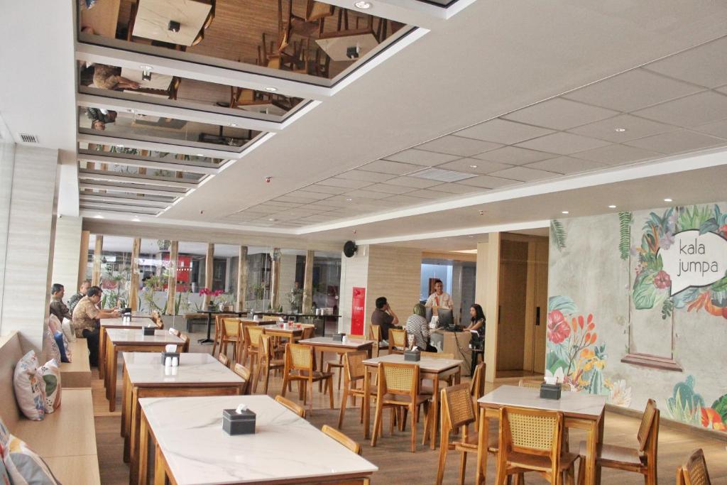 a restaurant with tables and chairs and people sitting in it at Aveta Hotel Malioboro in Yogyakarta