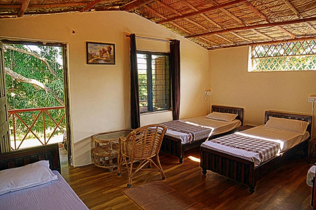 a room with three beds and a table and chairs at Nature Care Village- Rajaji National Park in Rishīkesh