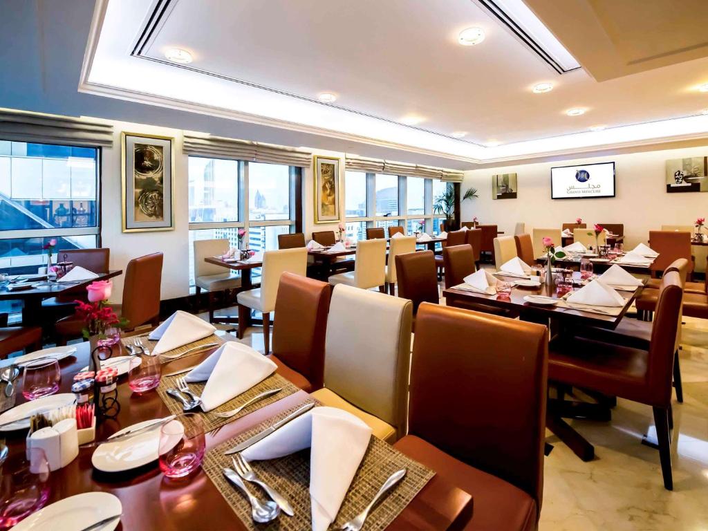 a dining room with tables and chairs in a restaurant at Grand Mercure Majlis Residences in Abu Dhabi