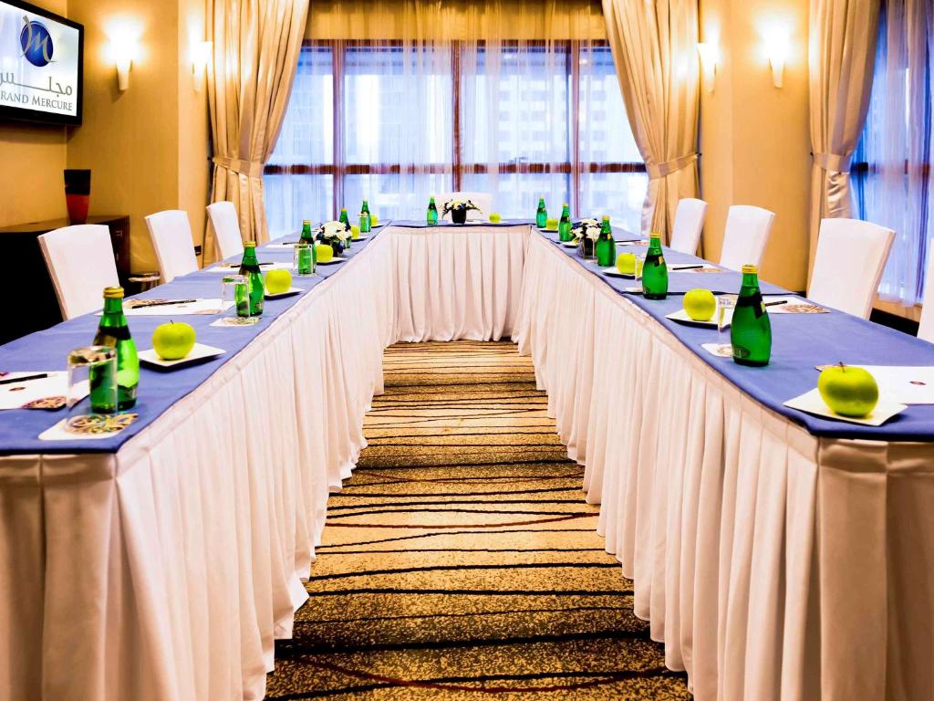 a long table with white table cloths and green bottles at Grand Mercure Majlis Residences in Abu Dhabi