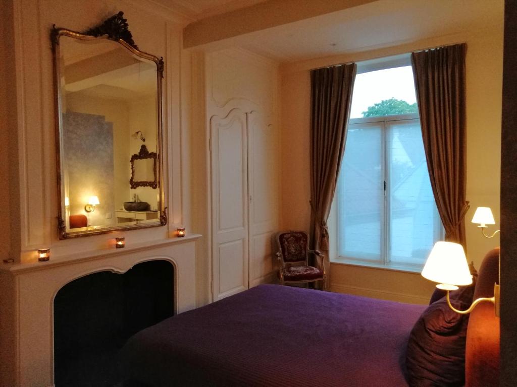 a bedroom with a bed and a mirror and a window at B&B Huis Willaeys in Bruges