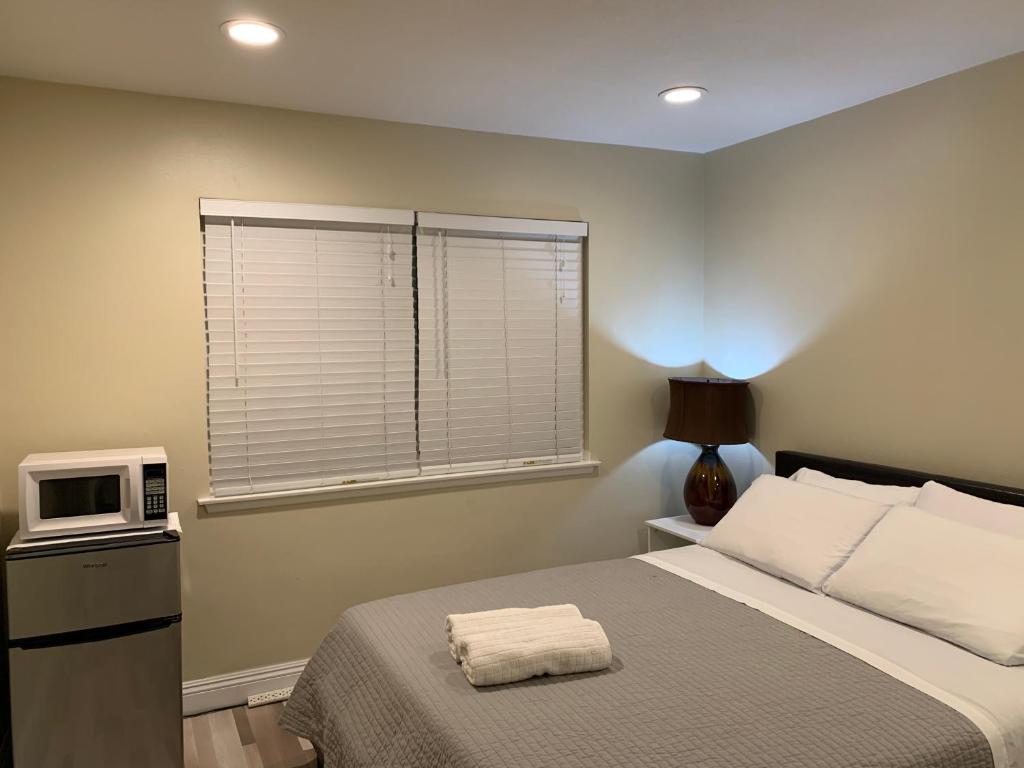 a bedroom with a bed with a microwave and a window at Lovely Room in Private House near Disneyland in Anaheim