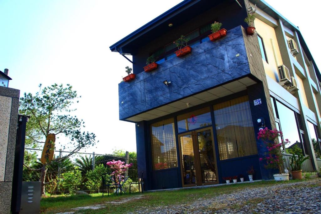 un bâtiment bleu avec des plantes en pot dans l'établissement YOJA B&B, à Puli