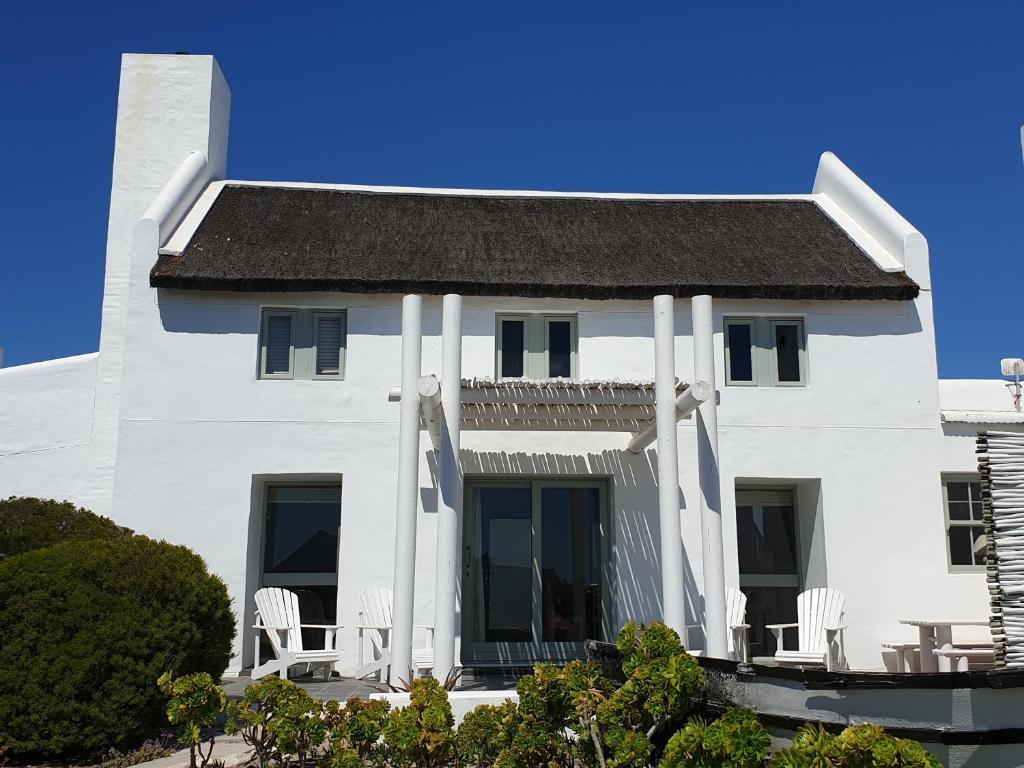 a white house with white chairs and a roof at Salt Water House in Paternoster