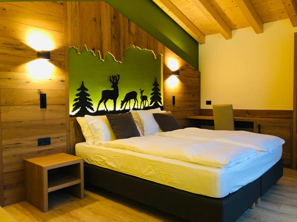 ein Schlafzimmer mit einem großen Bett und einem Hirschbild an der Wand in der Unterkunft Fulun Mountain Lodge in Giustino