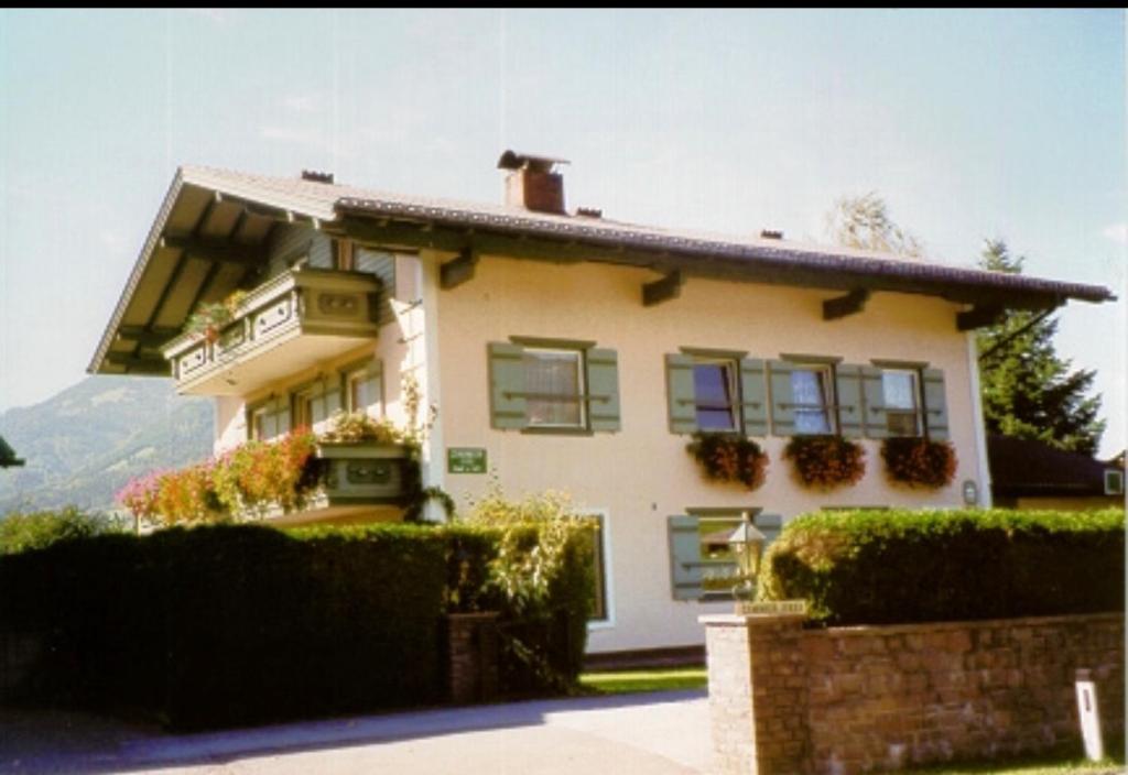 a house with green shuttered windows and bushes at Haus Kaindl in Kuchl