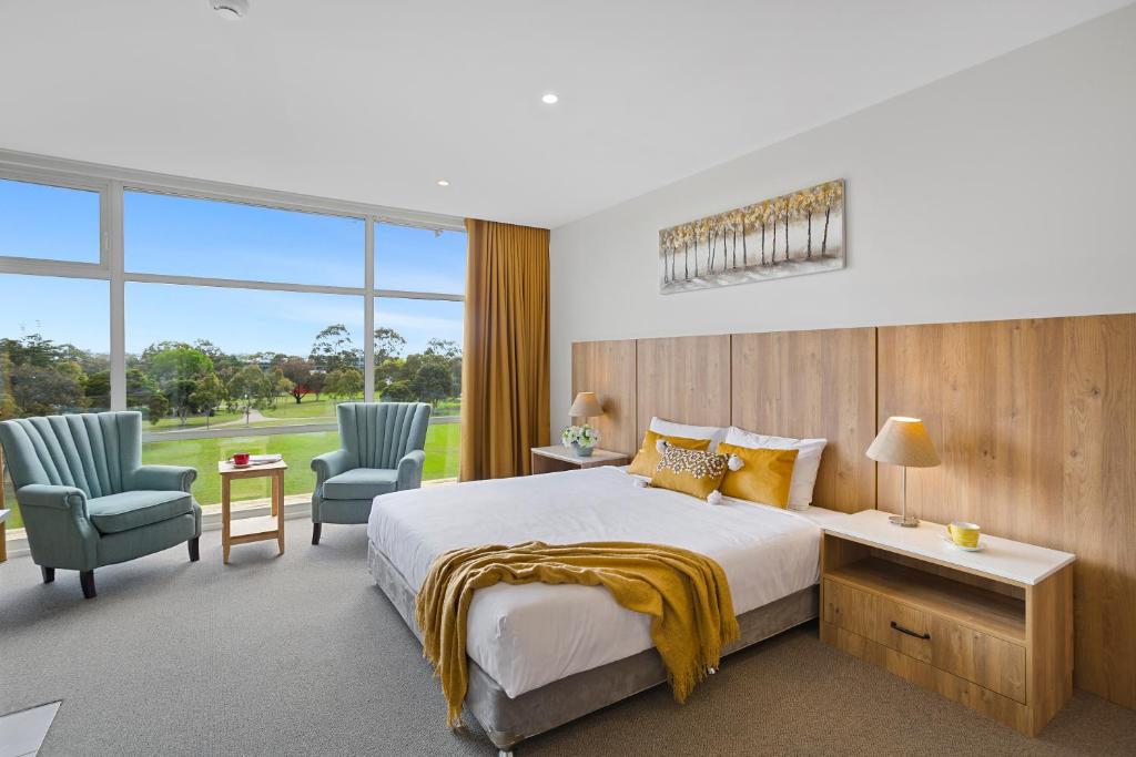 Parkside Motel Geelong في جيلونج: غرفة نوم بسرير كبير وكرسيين