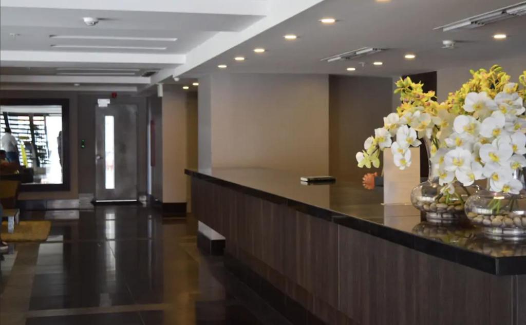 a lobby with a reception counter with white flowers on it at 1340 Quo Habitación en Lujoso Departamento a 1 minuto del Aeropuerto in Guayaquil