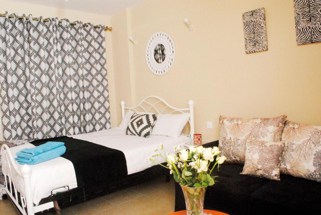 um quarto com uma cama branca e um sofá em WEST SUITES SHERRY HOMES em Nairobi