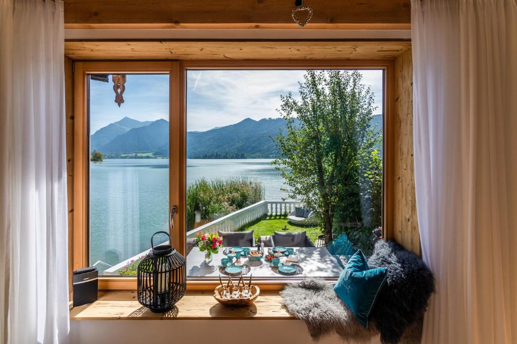 Habitación con ventana grande con vistas al agua. en Seeheimat Ferienwohnungen en Schliersee