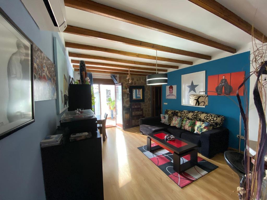 a living room with a black couch and blue walls at Vivienda turistica Pop Bowie House in Úbeda