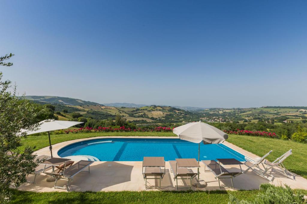 una piscina con sillas y sombrillas junto a en Villa del Cucco, en Fossombrone