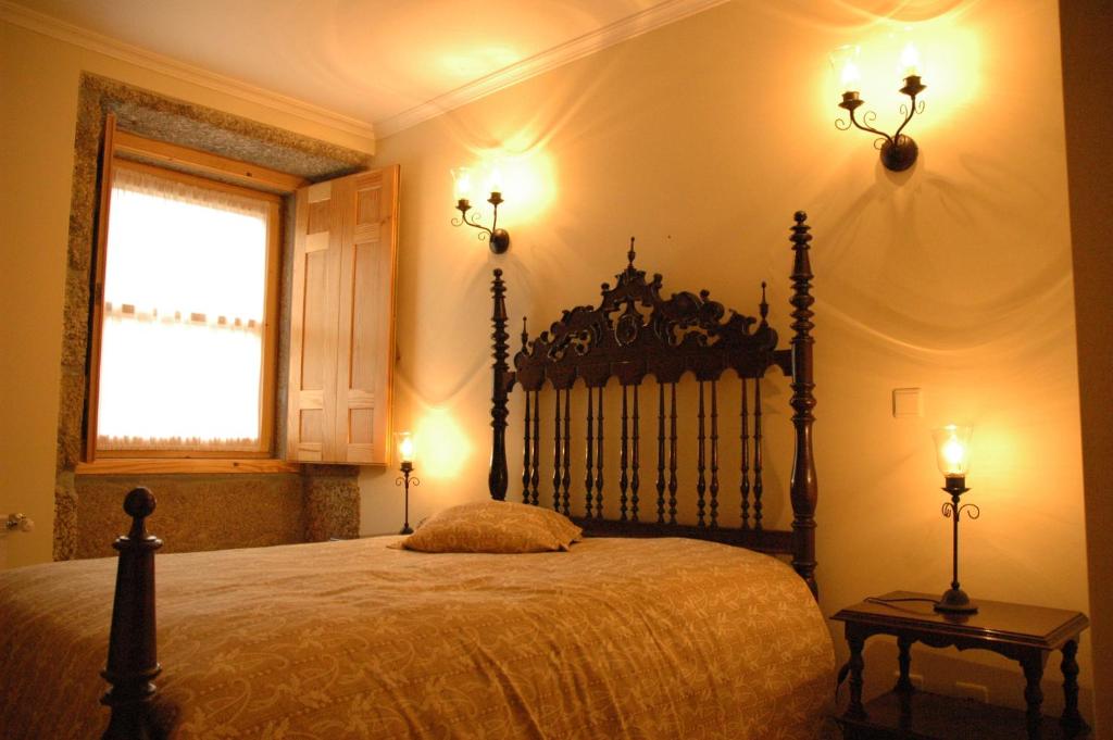 ein Schlafzimmer mit einem Bett mit zwei Lampen und einem Fenster in der Unterkunft Casa Avó Alice in Seia