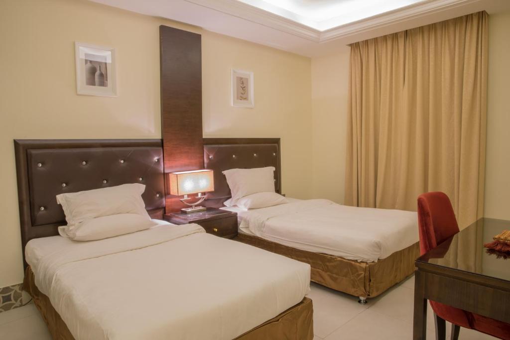 Habitación de hotel con 2 camas y escritorio en Alarjan Dream, en Riad