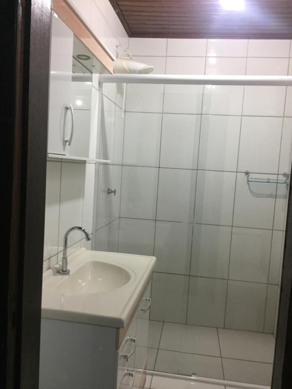een witte badkamer met een wastafel en een douche bij Suíte Maciel in Foz do Iguaçu