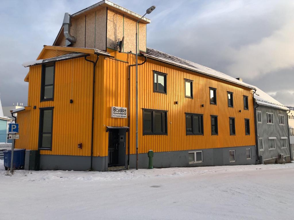 a large yellow building in the snow at Brygga Gjestehus in Harstad