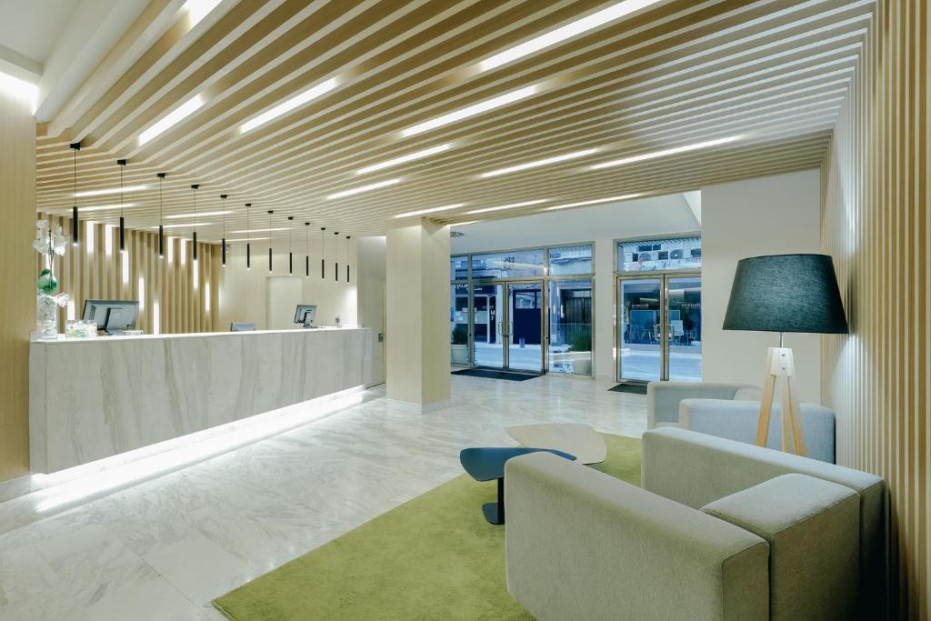een lobby met een wachtruimte met een bank en stoelen bij Hesperia Murcia Centro in Murcia